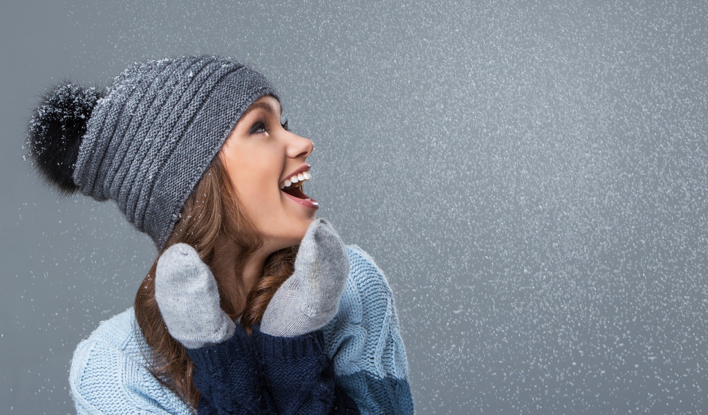 Девушка в теплой шапке на сером фоне