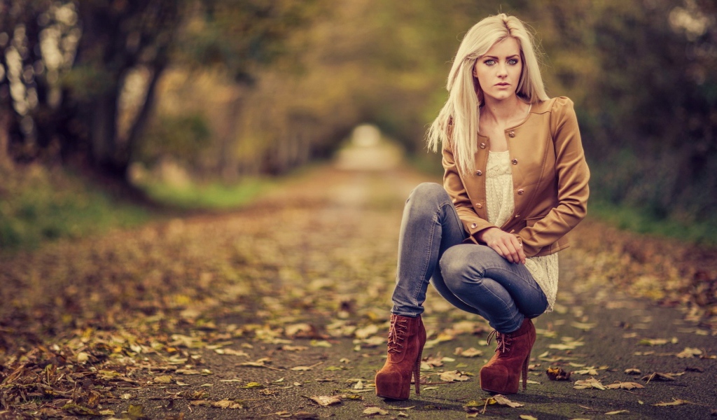 Девушка на высоких каблуках сидит на корточках в парке