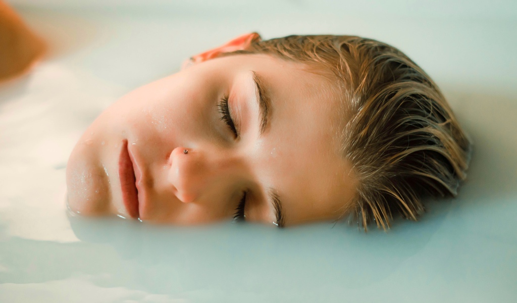Девушка лежит с закрытыми глазами в ванной
