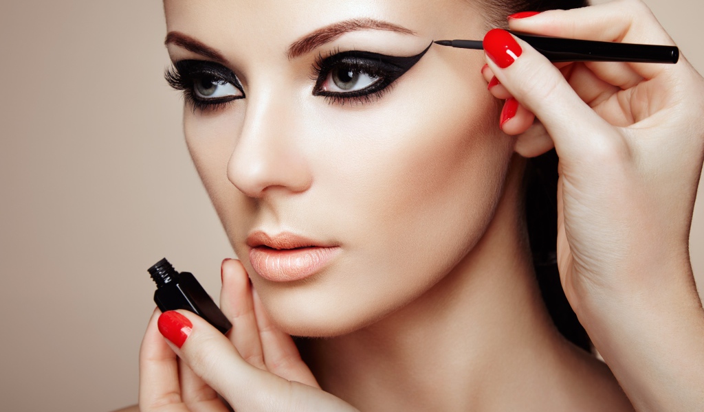 Девушке красят глаза черной подводкой 