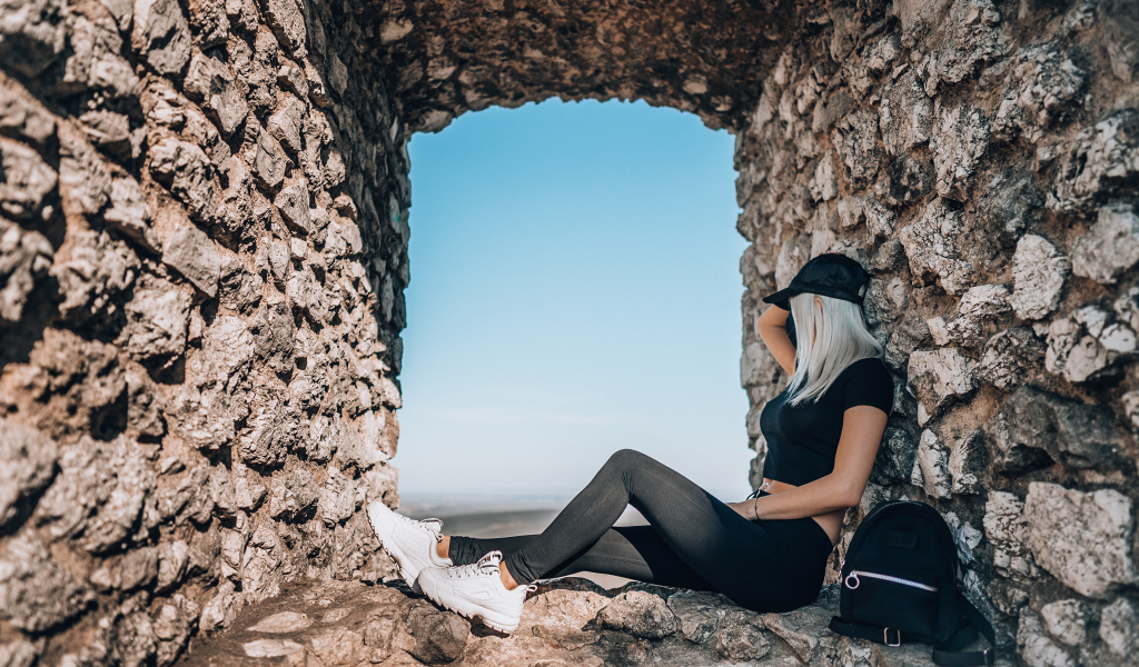 Девушка сидит в окне старого здания 