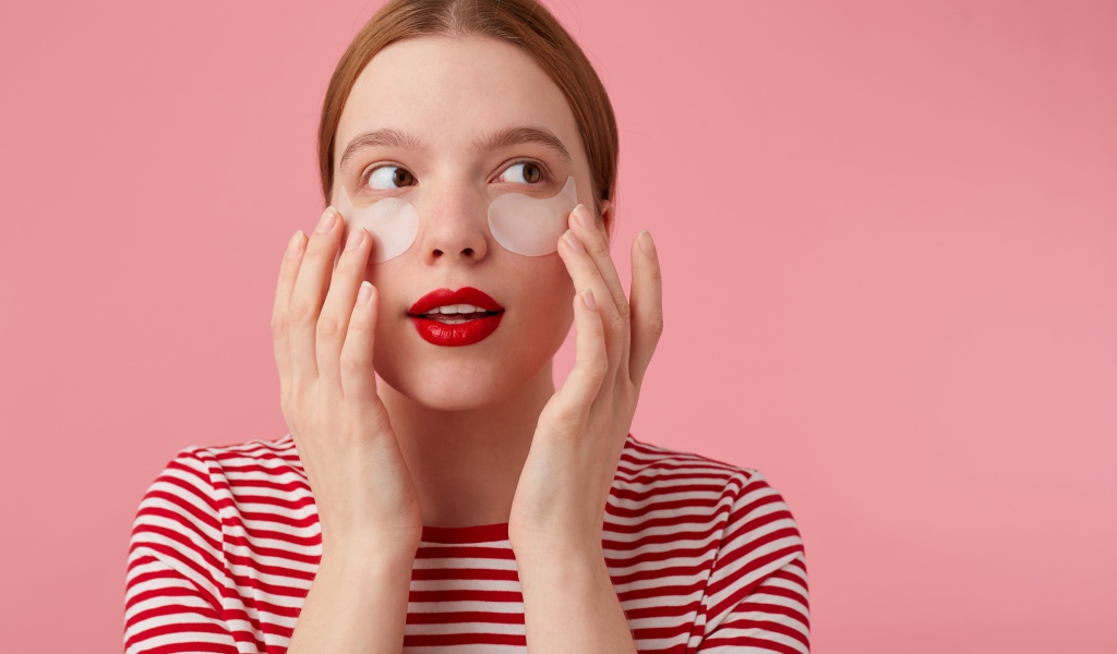 Девушка приклеивает патчи для глаз на лицо 