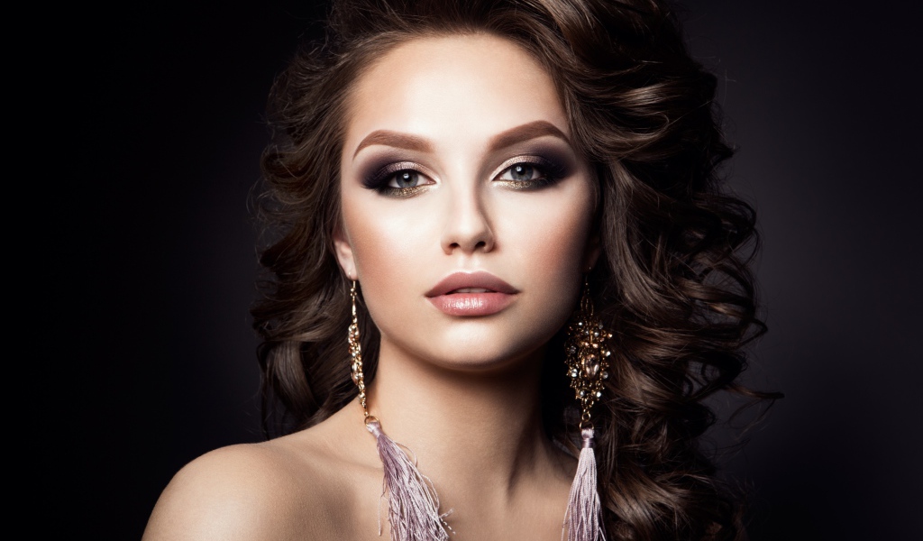 Девушка с прической с красивыми сережками на сером фоне 