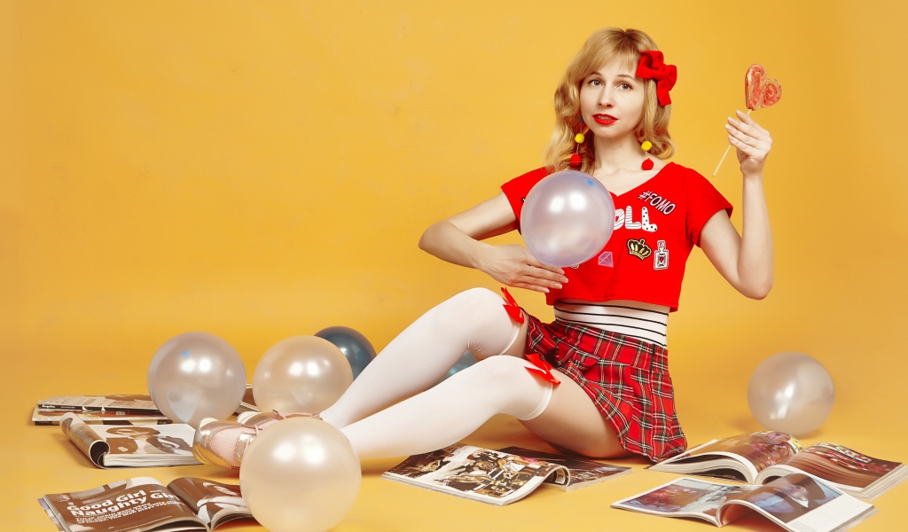 Девушка с шариками и журналами сидит на полу