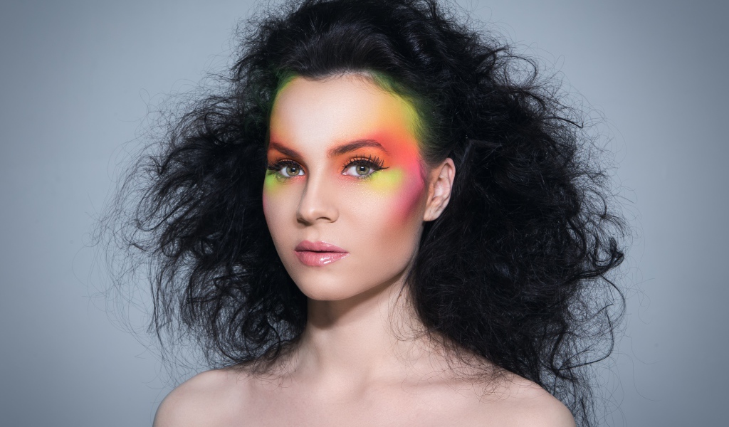 Девушка с начесом на волосах с ярким макияжем на сером фоне