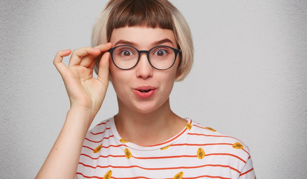 Девушка с короткой стрижкой поправляет очки 