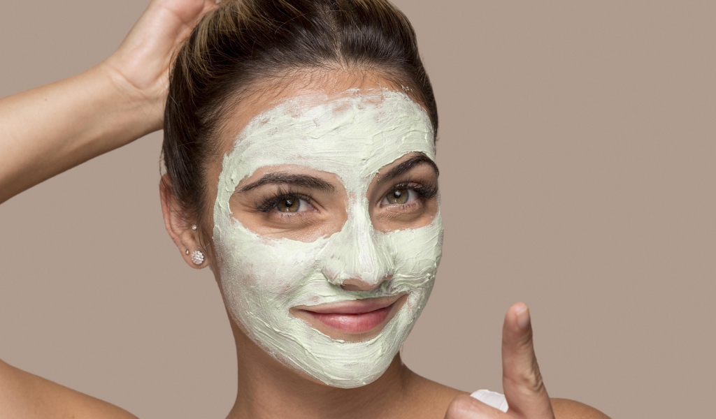 Девушка с завязанными волосами с косметической маской на лице