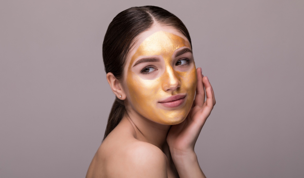 Золотая маска на лице у молодой девушки 