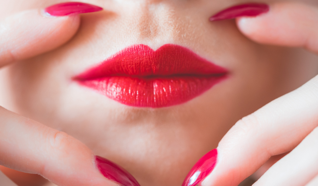 Руки с длинными красными ногтями у губ