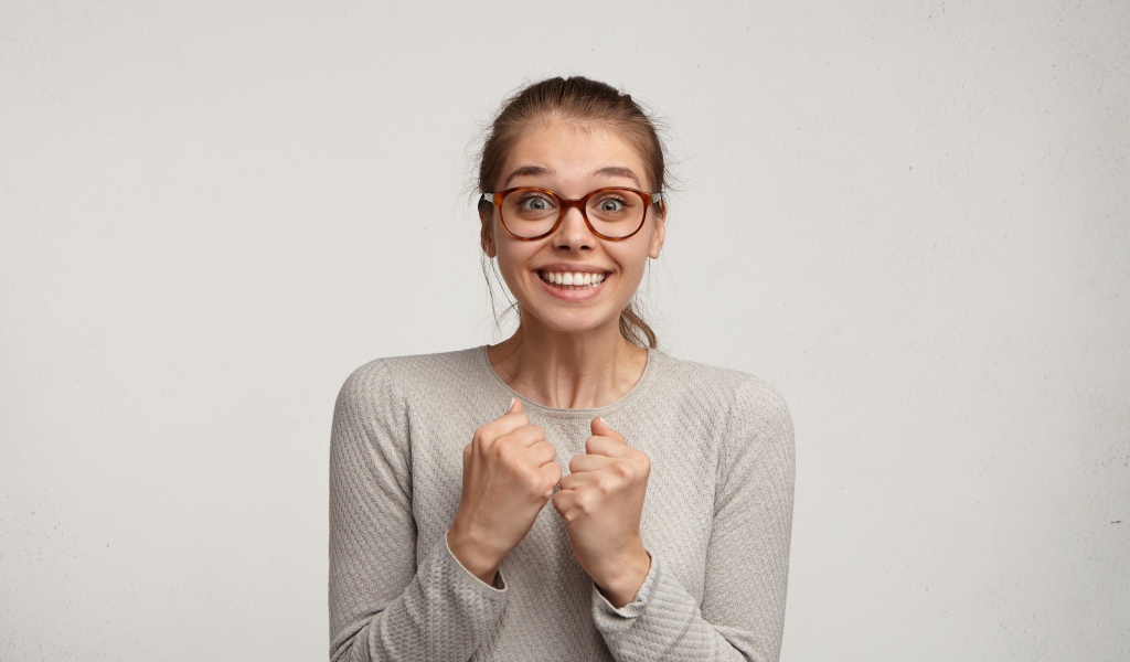 Радостная девушка в очках для зрения на сером фоне 