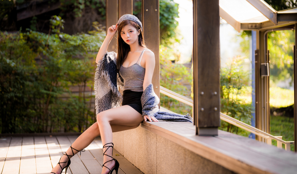 Длинноногая азиатка сидит на окне 