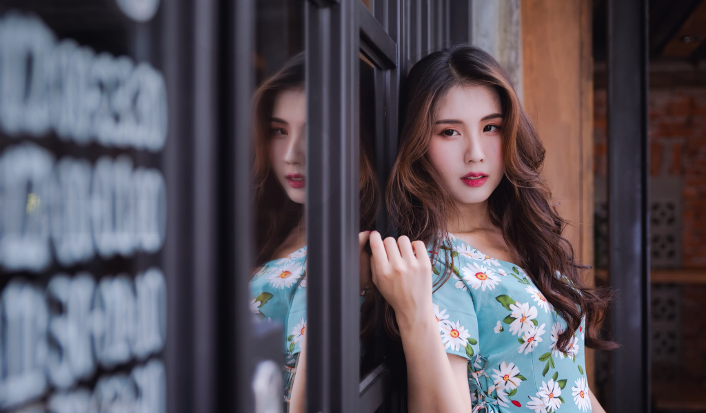 Длинноволосая девушка азиатка стоит у окна