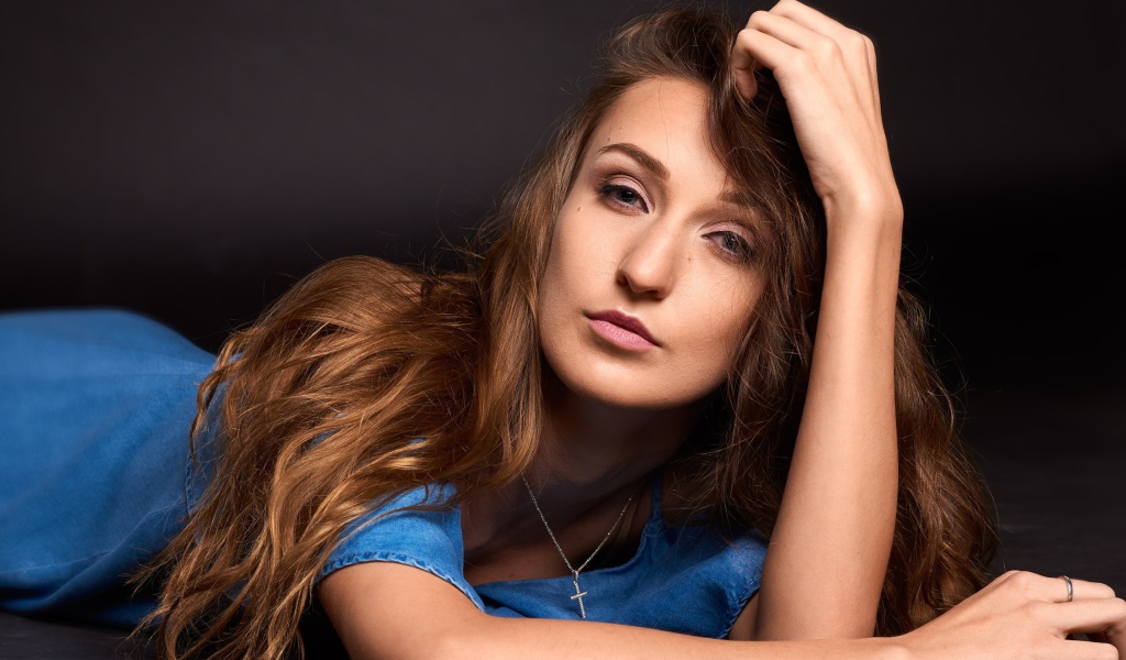 Длинноволосая шатенка лежит на полу в голубом платье 