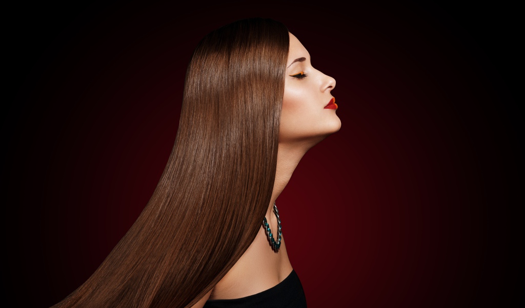 Длинноволосая шатенка с закрытыми глазами на красном фоне