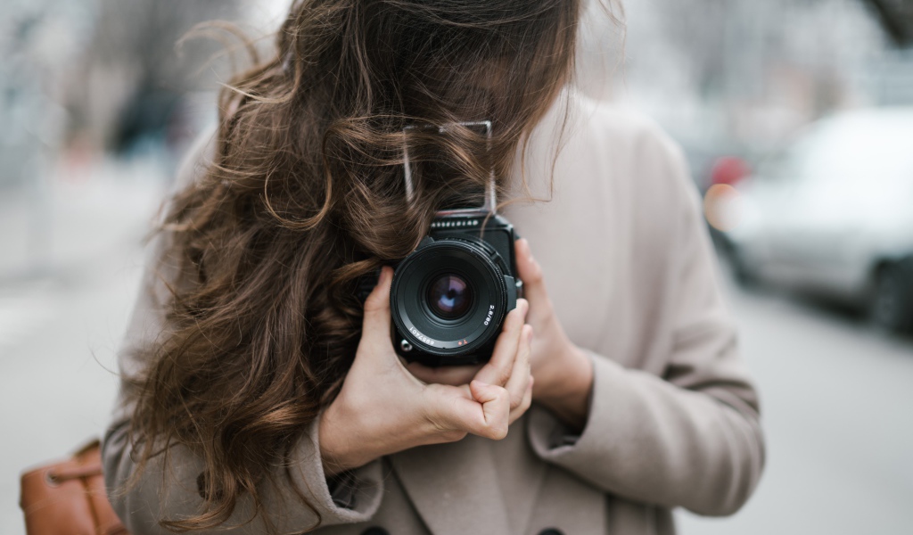 Длинноволосая девушка с фотоаппаратом в руках 