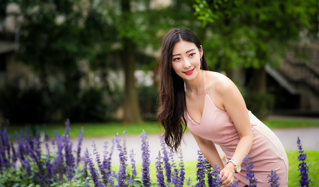 Милая девушка Азиатка в розовом платье у синих цветов