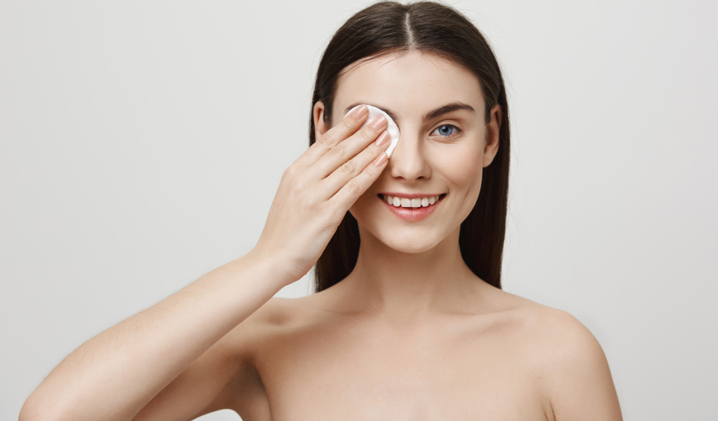 Настоящая голубоглазая девушка снимает макияж с лица