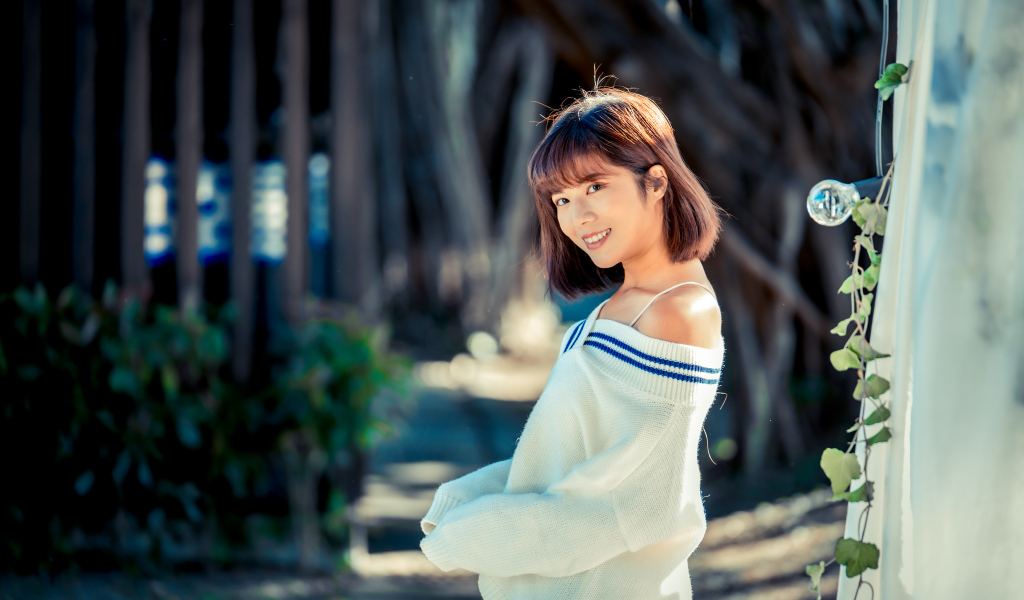 Улыбающаяся девушка азиатка в белом свитере 