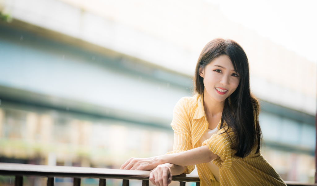 Улыбающаяся азиатка в желтой полосатой рубашке