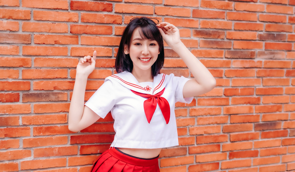 Улыбающаяся азиатка стоит у стены 