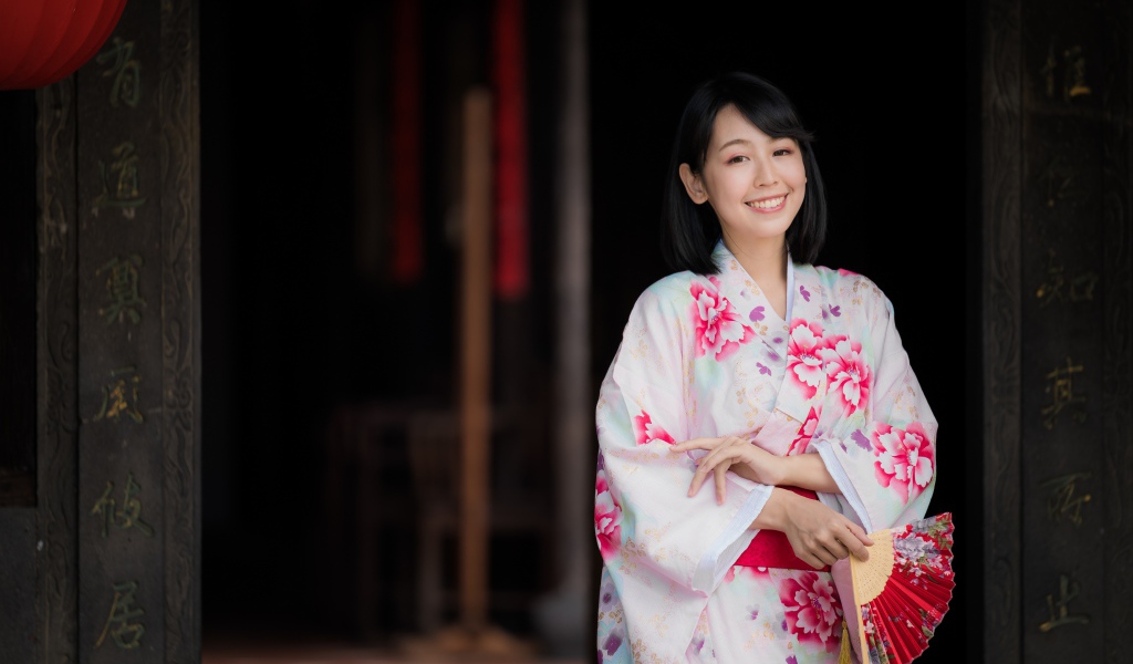 Улыбающаяся девушка азиатка в кимоно с веером в руке