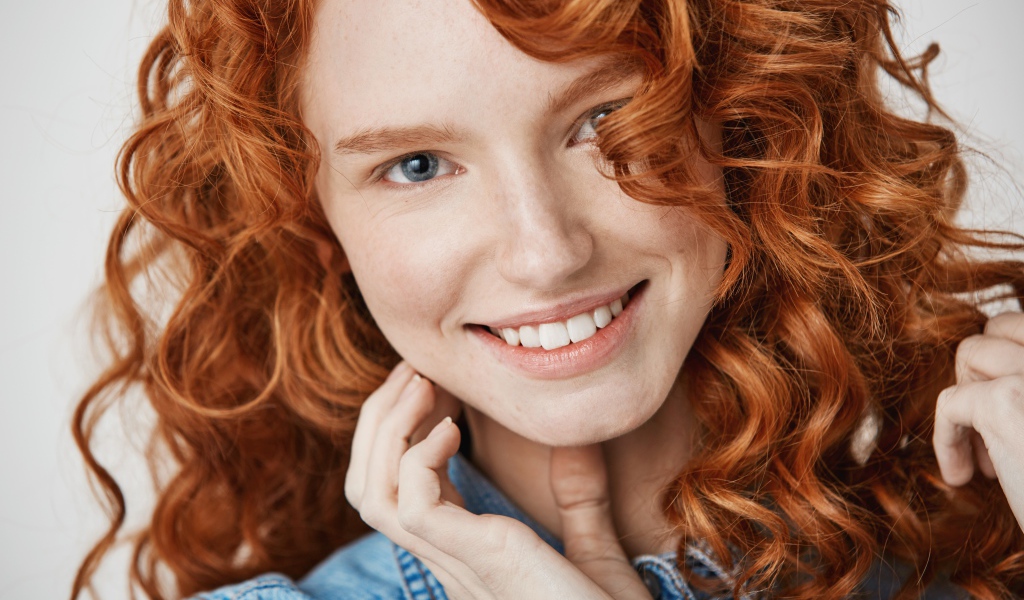 Улыбающаяся голубоглазая рыжеволосая девушка в джинсовой куртке 