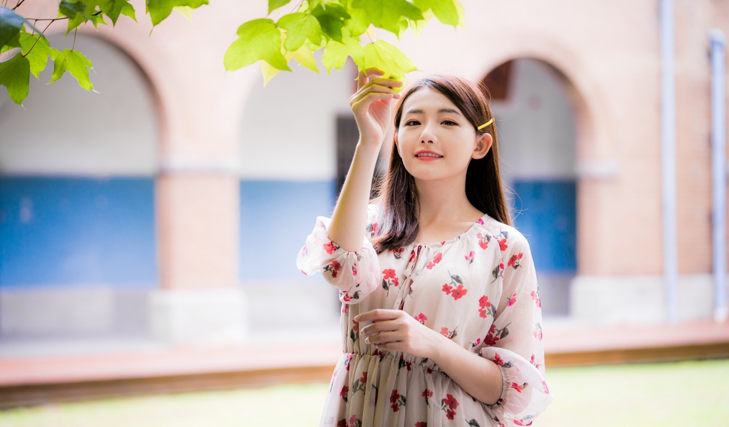 Улыбающаяся девушка в платье у дерева 