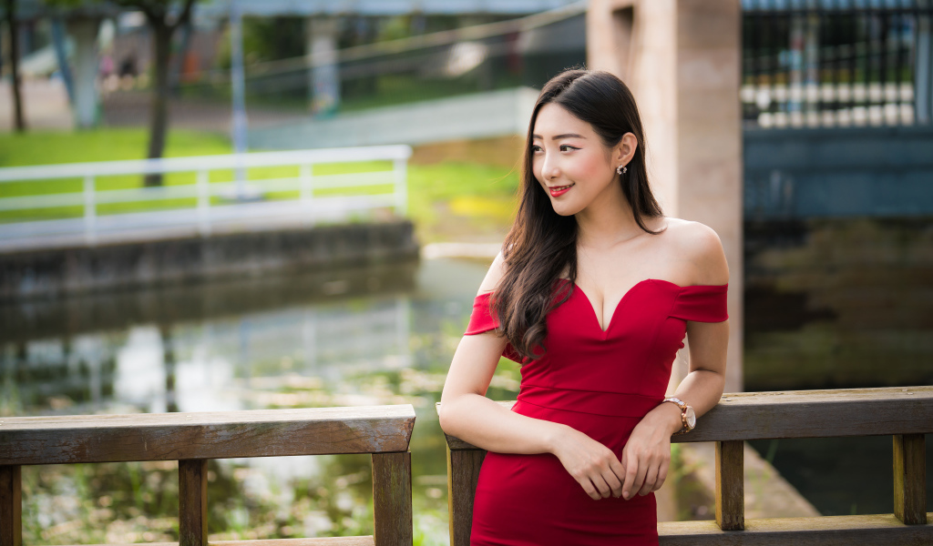 Улыбающаяся девушка в красном платье у перил 