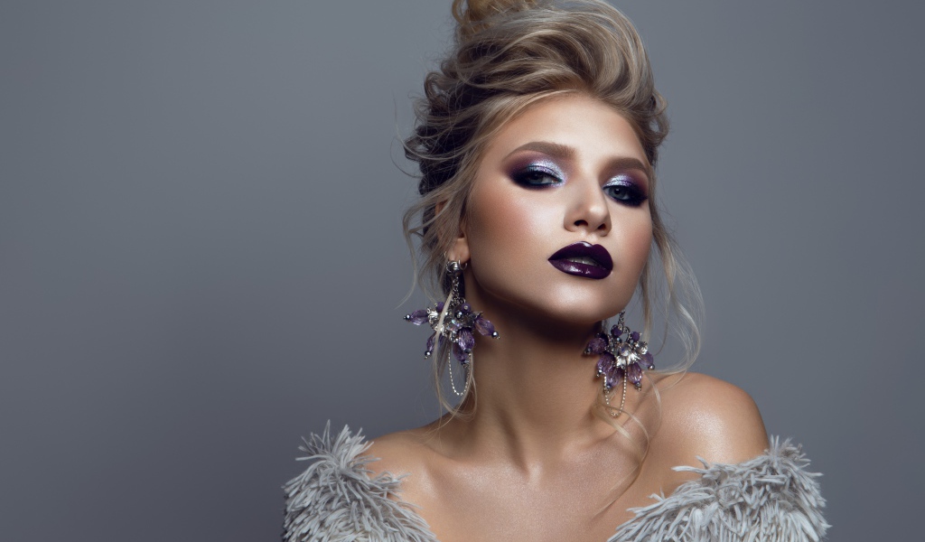 Эффектная девушка с ярким макияжем на сером фоне