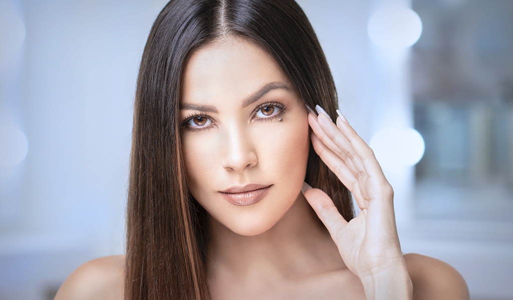 Стильная кареглазая длинноволосая брюнетка с рукой у лица