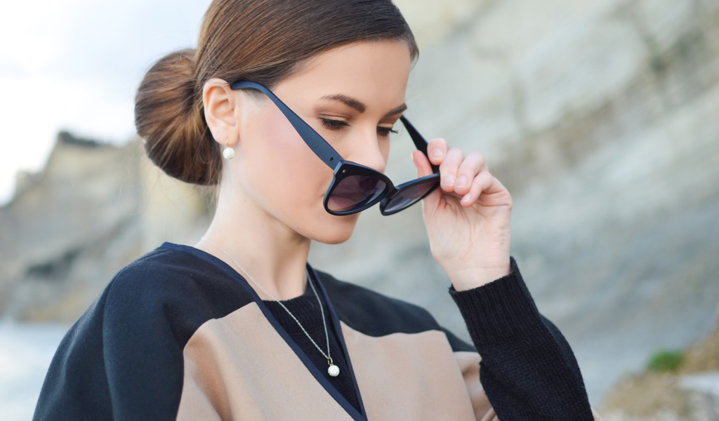 Стильная девушка с прической снимает очки