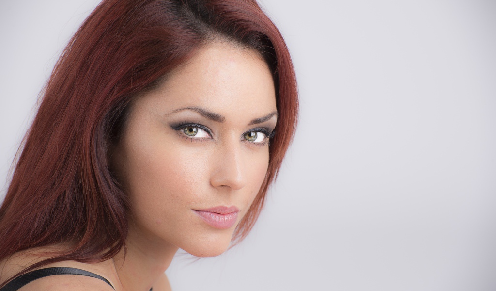 Лицо стильной девушки с зелеными глазами на сером фоне