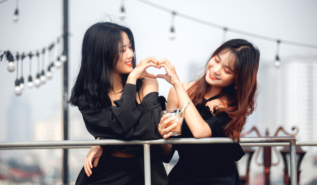 Две девушки азиатки делают сердце руками 