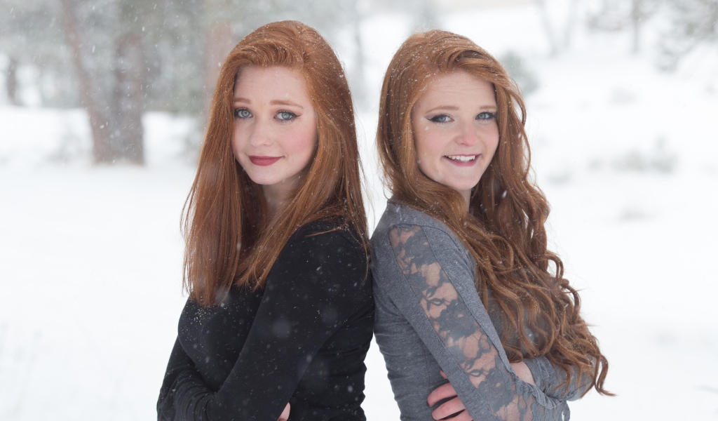 Две улыбающиеся рыжеволосые сестры на улице зимой 
