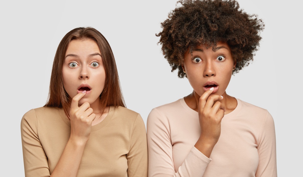 Две удивленные девушки на сером фоне 