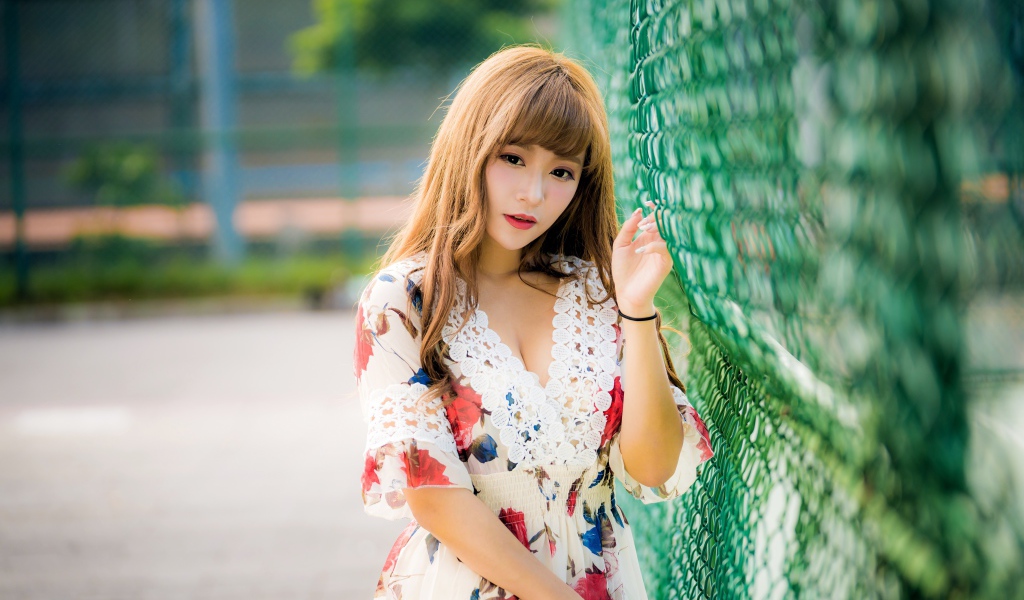 Молодая азиатка в платье у зеленой сетке 