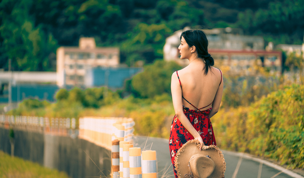 Молодая девушка азиатка в сарафане со шляпой в руке 