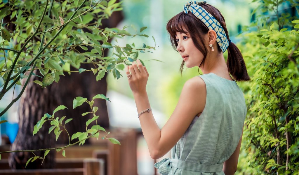 Молодая девушка азиатка с повязкой на голове у дерева 