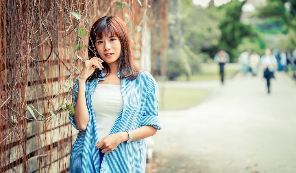 Молодая азиатка в рубашке у стены