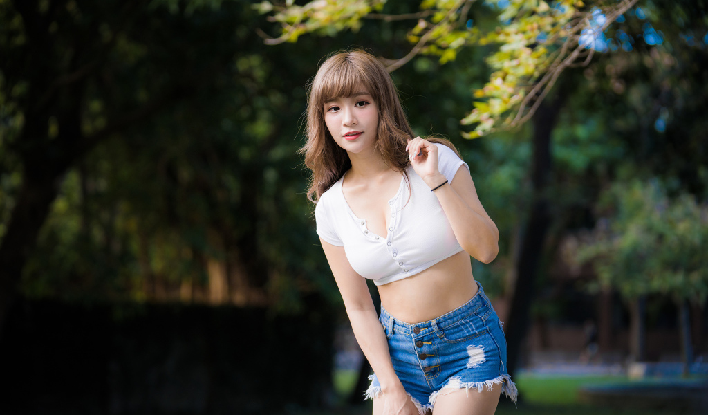 Молодая азиатка в белом топе и синих шортах  в парке