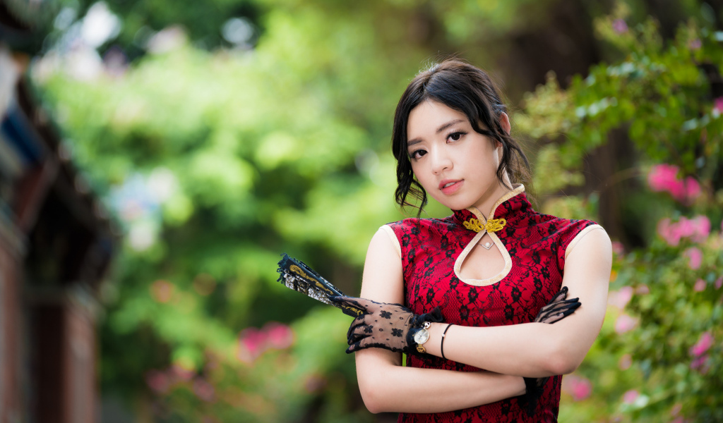 Молодая азиатка в красивом платье с веером в руке