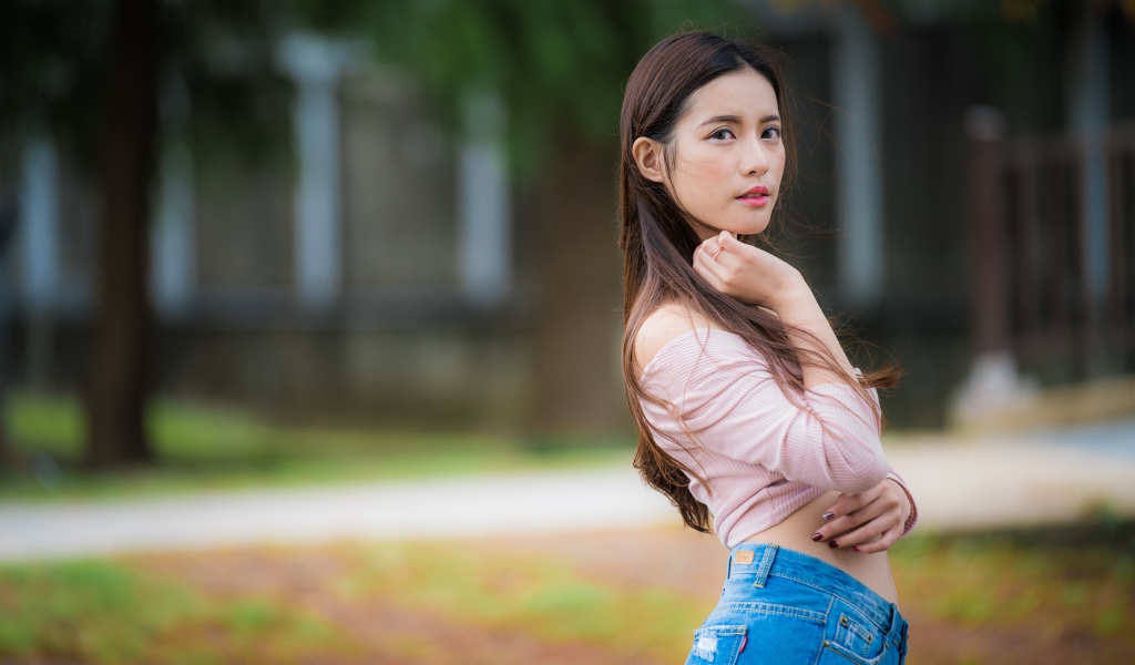 Молодая азиатка с длинными волосами в синих джинсах