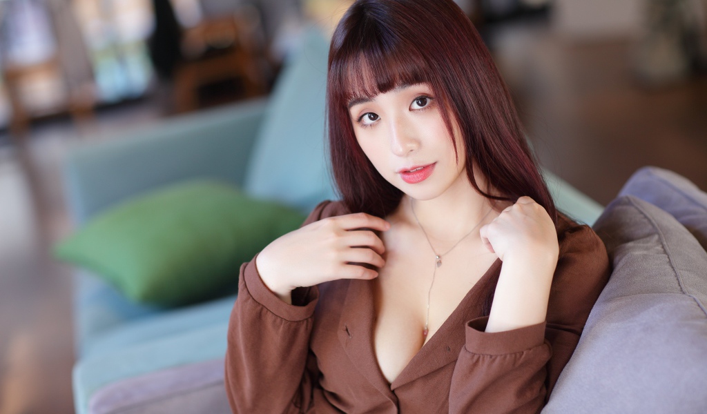 Молодая азиатка сидит на диване 