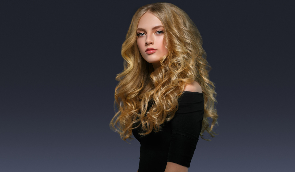 Молодая блондинка с красивыми длинными волосами в черном платье