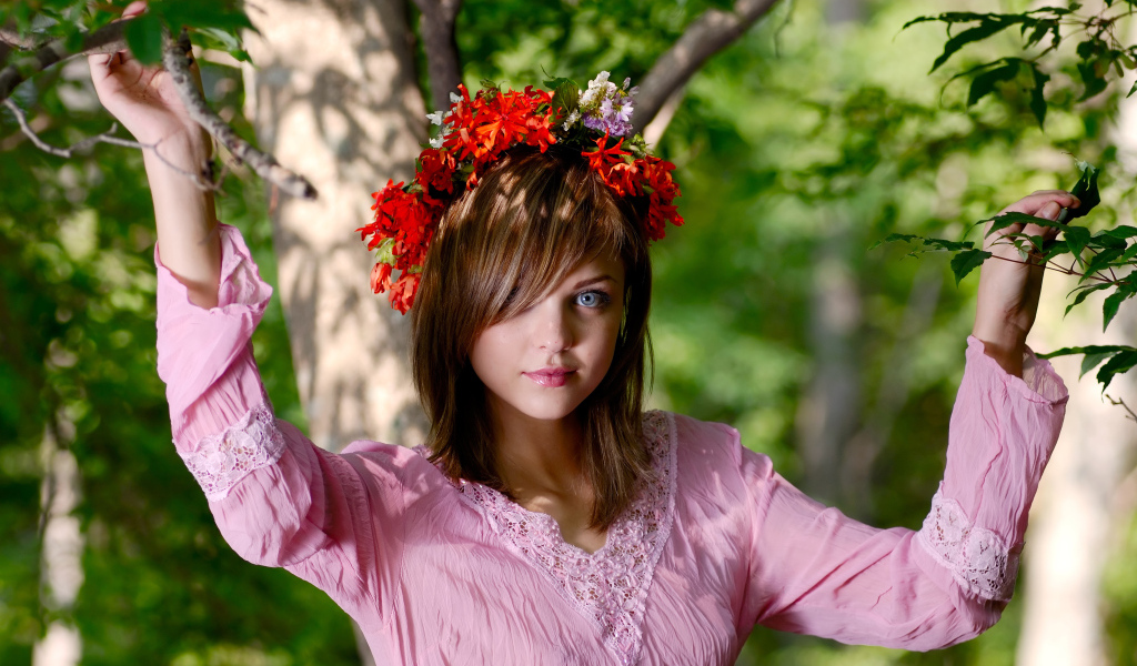 Молодая милая голубоглазая девушка с венком на голове у дерева