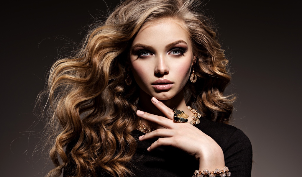 Молодая девушка в черном свитере с дорогими украшениями