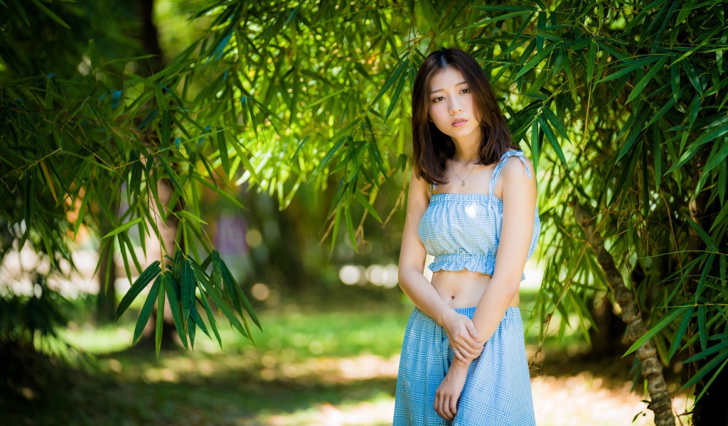 Молодая девушка в голубом костюме под деревом