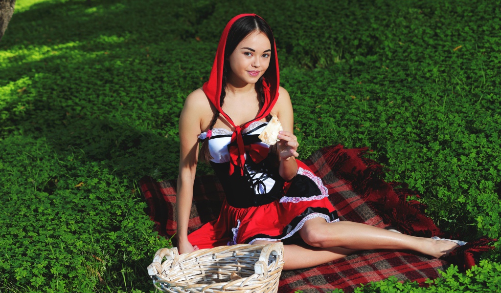 Молодая девушка в костюме сидит на траве, косплей