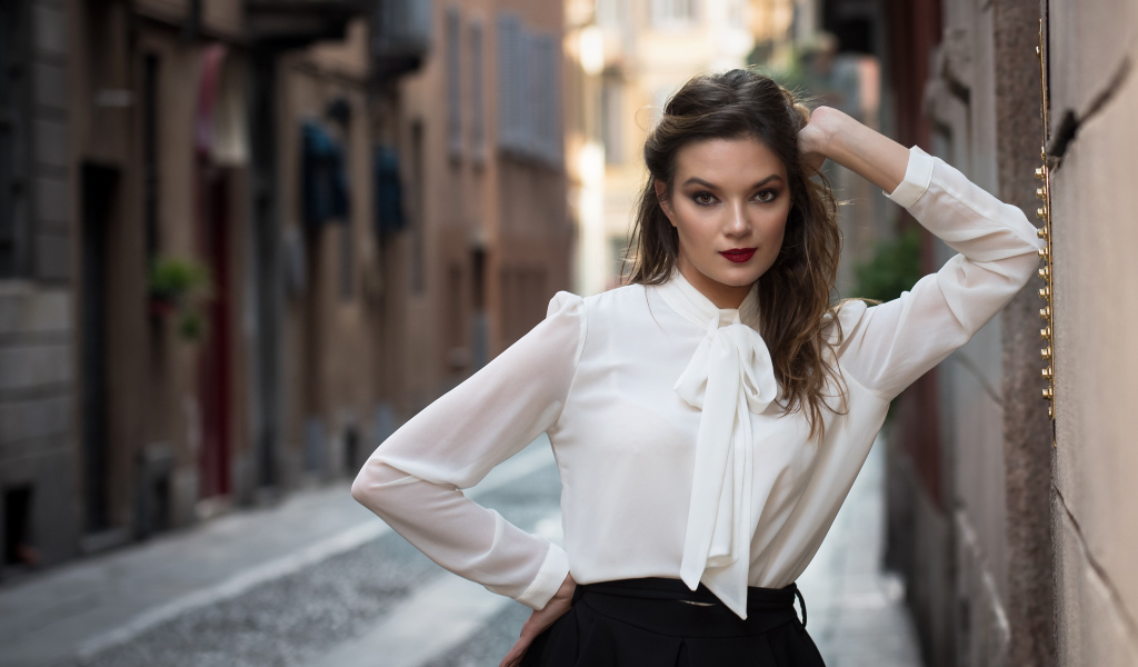 Молодая девушка в белой рубашке у стены