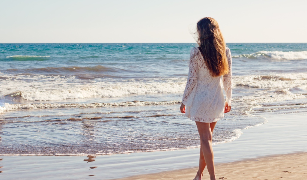 Молодая девушка в белом кружевном платье у моря